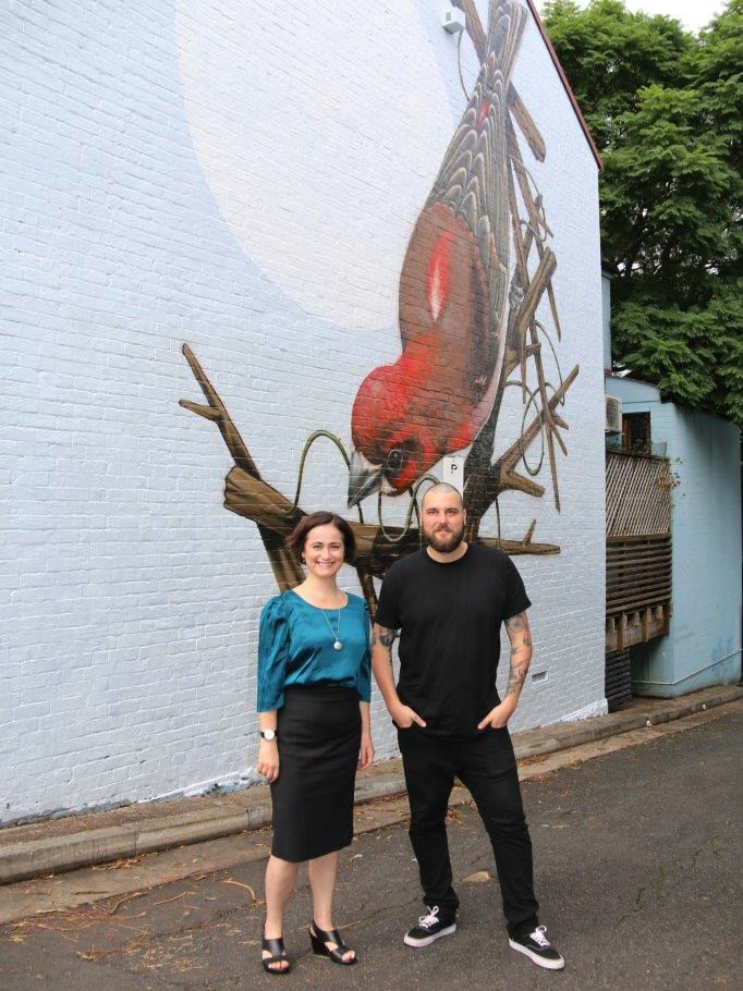 Bridget Haire with artist Thomas Jackson beside the mural he painted on her wall at Camperdown in Sydney's inner west.