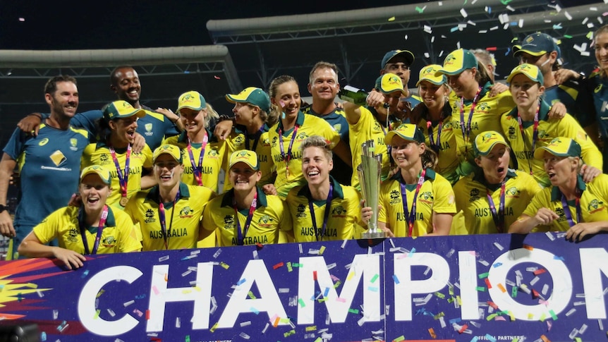 Australia's cricketers celebrate behind a 'CHAMPIONS' banner and lift a trophy as confetti flies.