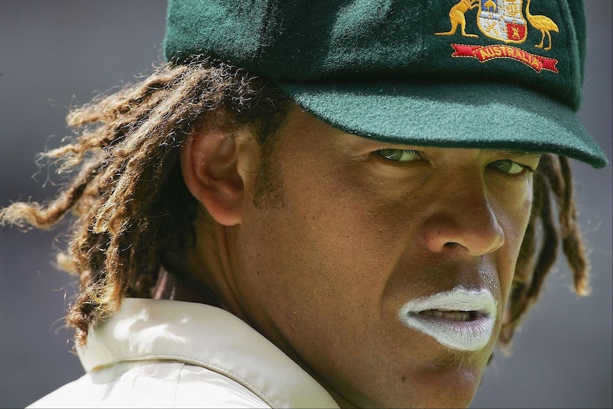 Close-up photo of Andrew Symonds, wearing baggy green cap, dreadlocks and white zinc on both lips