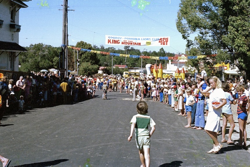 A large crowd gather around a finish line in 1979 on a local street Pomona. The image is old and faded.
