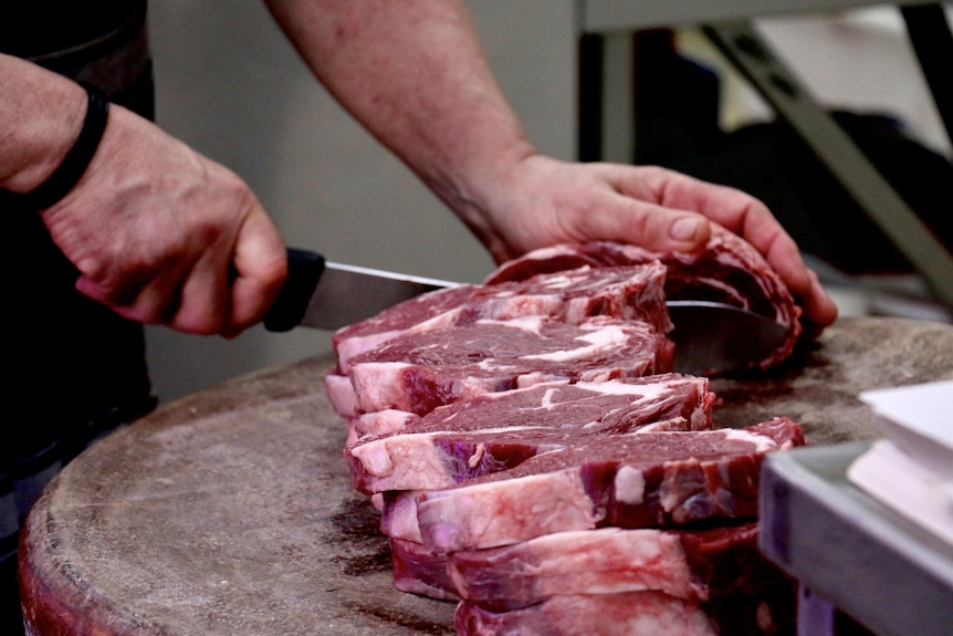 A man slices meat on a cutting board