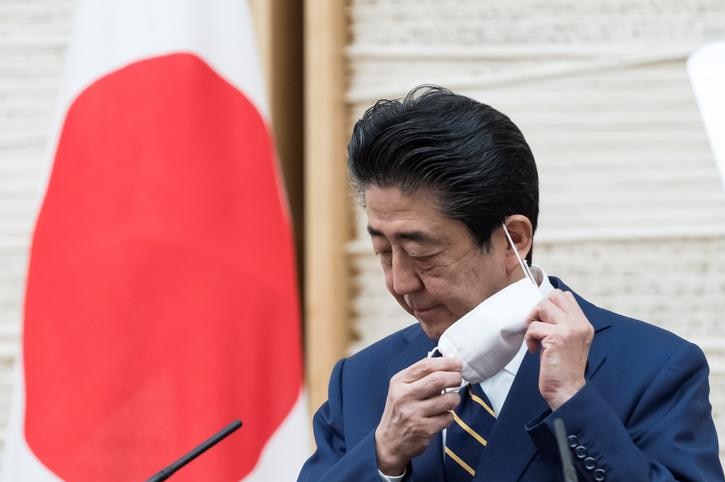 Japan's Prime Minister Shinzo Abe removes a face mask