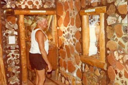 A historical photo of a man standing in a pretend underground mine full of gemstones.