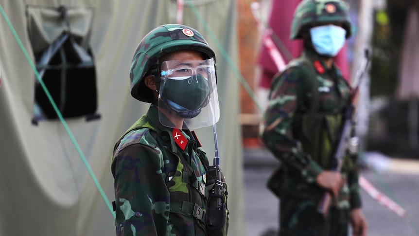 Armed military troops in full PPE stand guard outside a testing tent