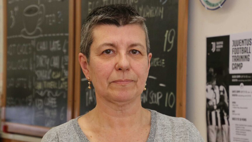 Cafe owner Ada Guglielmino stands in front of black board in cafe
