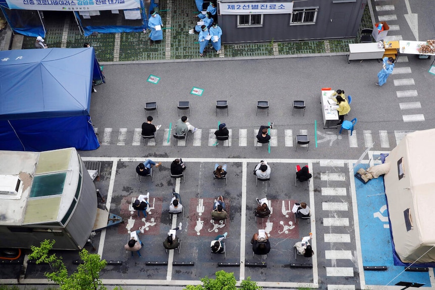 A birds eye view of a testing facility in Seoul where several people are waiting to be tested.