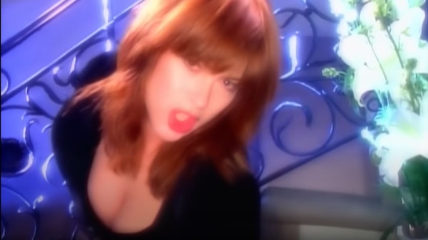 Chrissy Amphlett pouts for the camera by a stairwell and vase of white flowers for 'I Touch Myself' music video