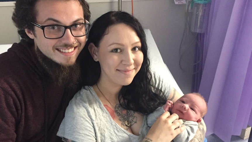 Two parents in hospital with a newborn baby.