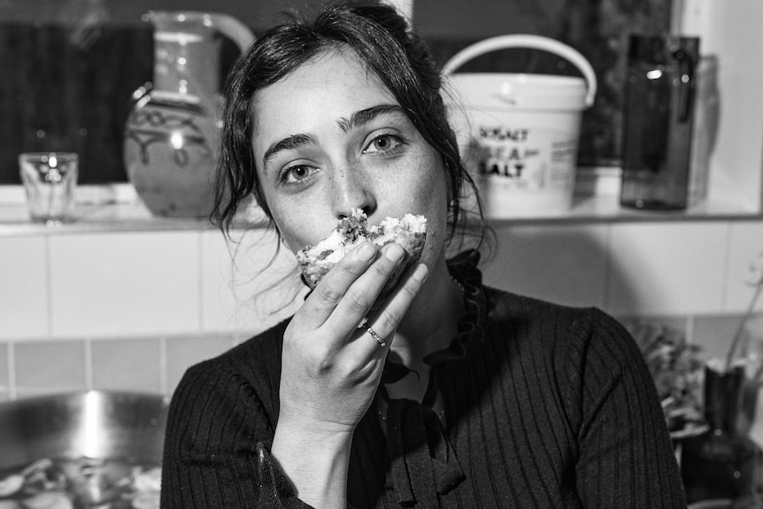 Woman poses for a photo at home while eating, a chef sharing how she celebrates Hanukkah.