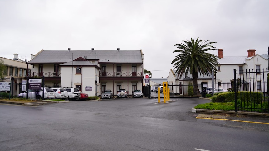 Large white buildings with a fence and cars 