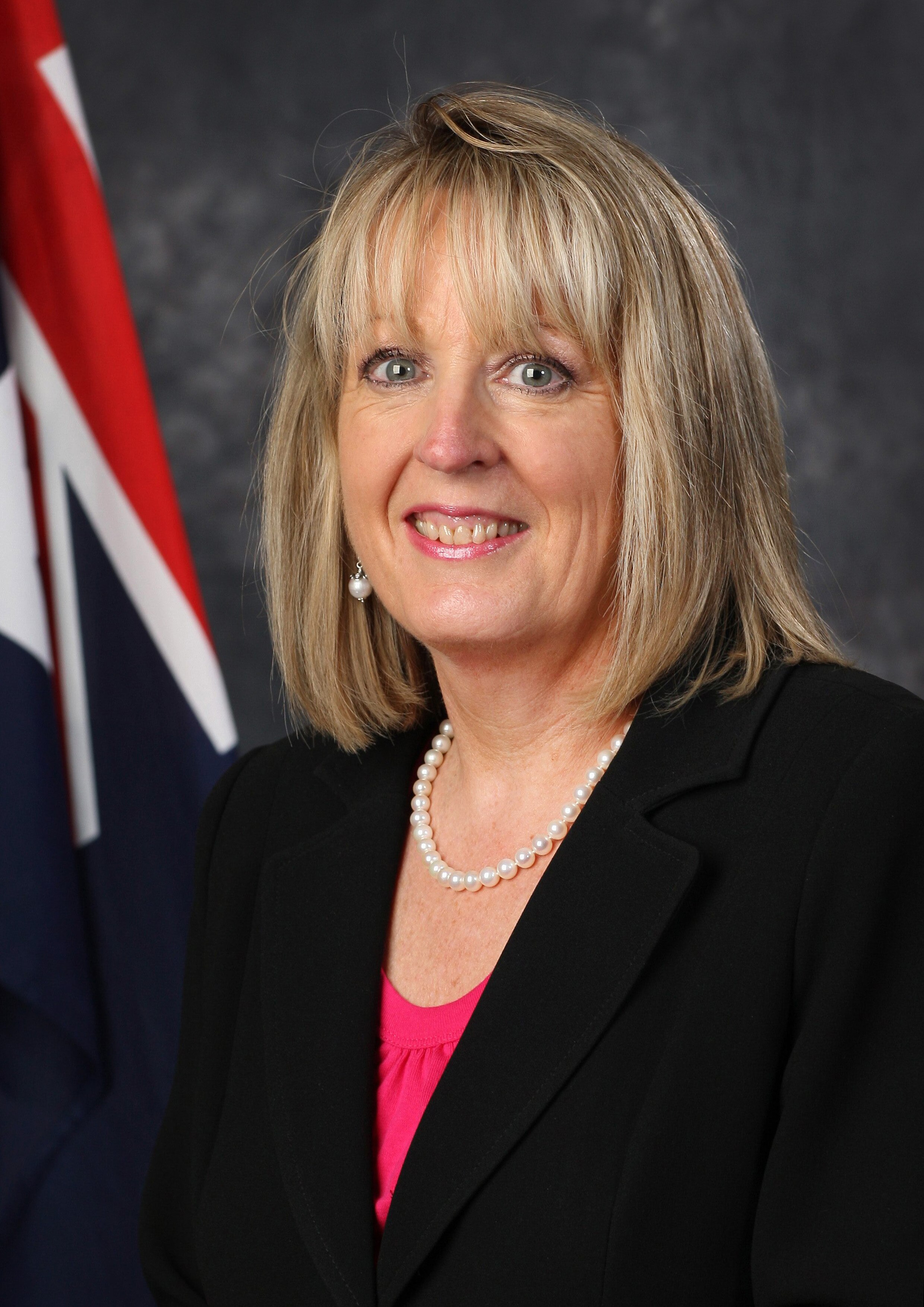 Liz Cosson smiles with an australian flag behind her