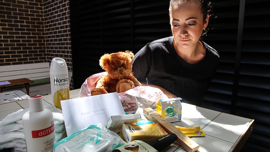 A woman sits at a table looking at all the items contained within an Escabag.