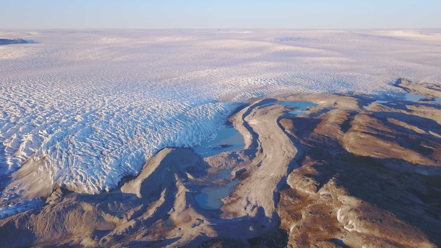 An aerial view showing the Greenland ice sheet meeting bare land.