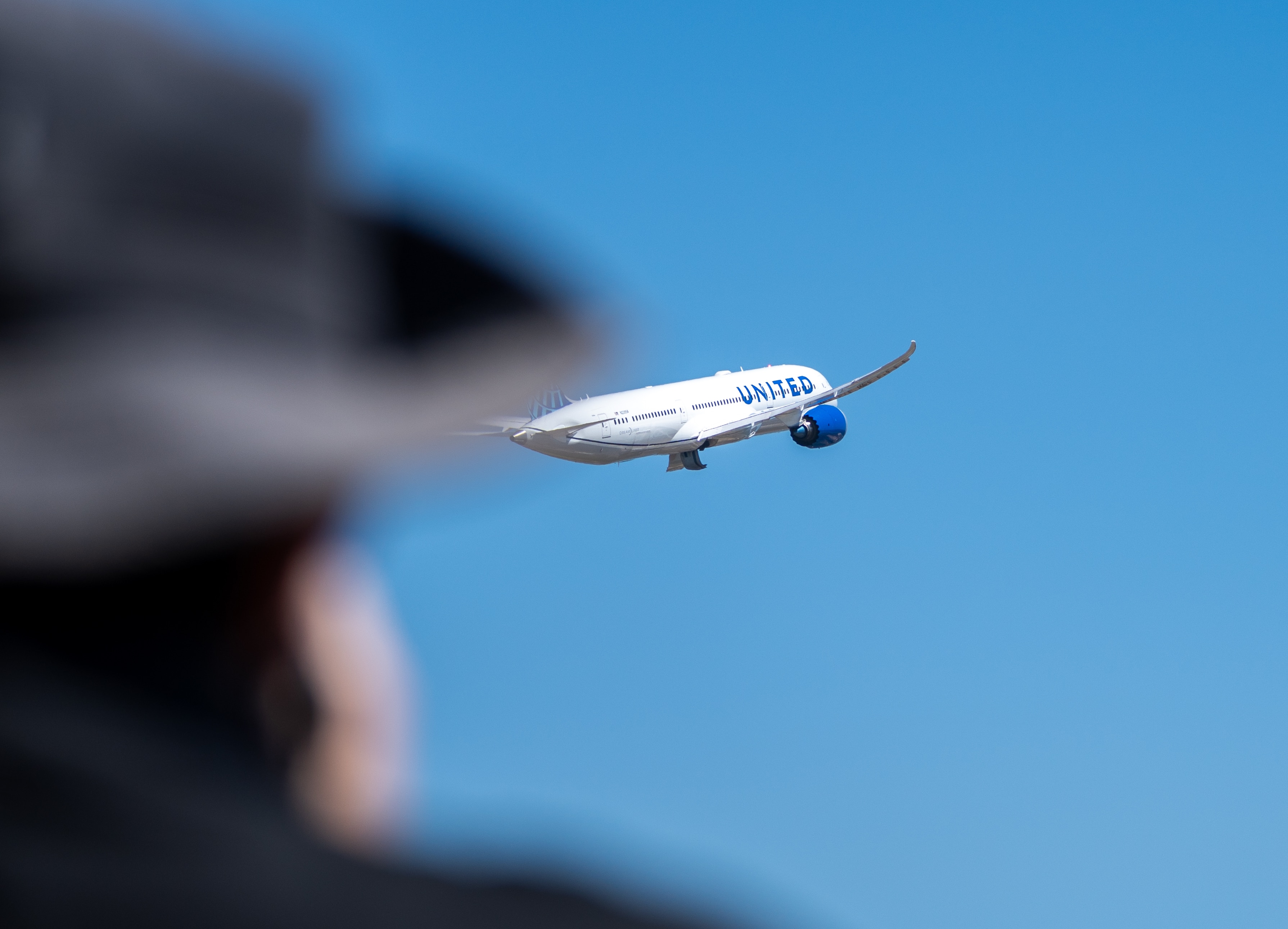 Un gran avión vuela con un sombrero en primer plano.