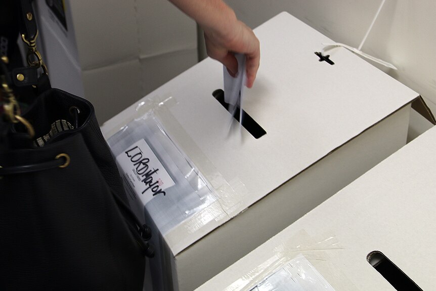 A person puts their ballot paper in the ballot box for the NT council elections at a voting centre in Mitchell Street, Darwin.
