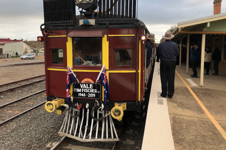 An old train waits at a station platform