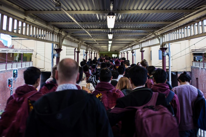 Commuters exit a train and walk up the ramp at South Yarra station.