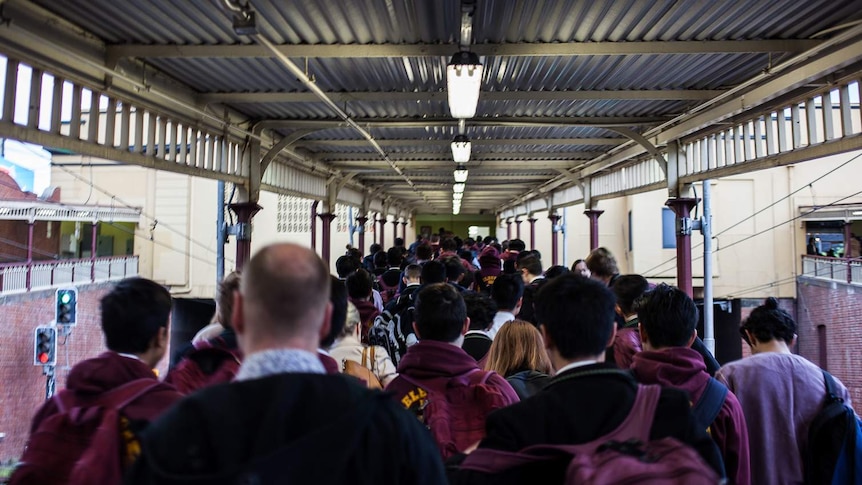 Commuters exit a train and walk up the ramp at South Yarra station.