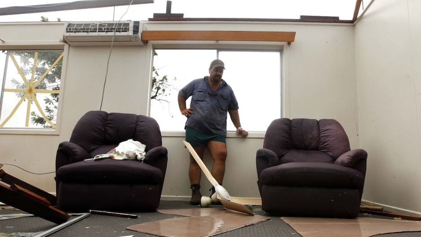 Jamie Faulks looks at debris in his house after the roof was blown off by Cyclone Yasi in Silkwood