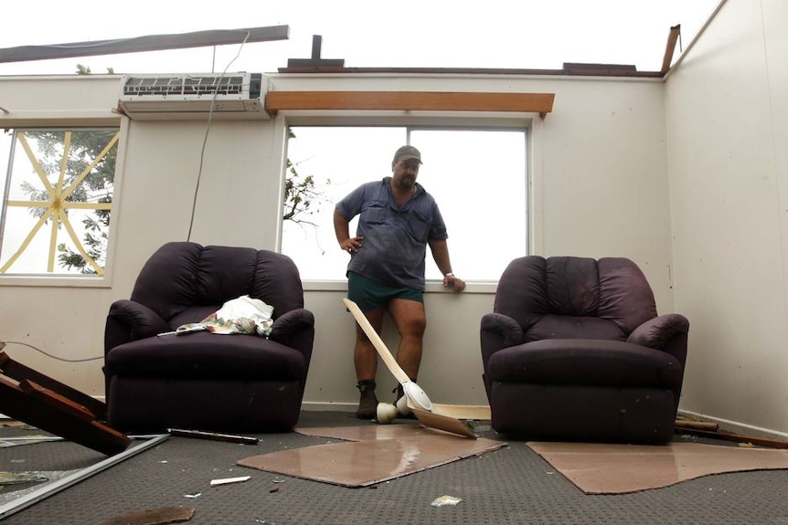 Jamie Faulks looks at debris in his house after the roof was blown off by Cyclone Yasi in Silkwood.