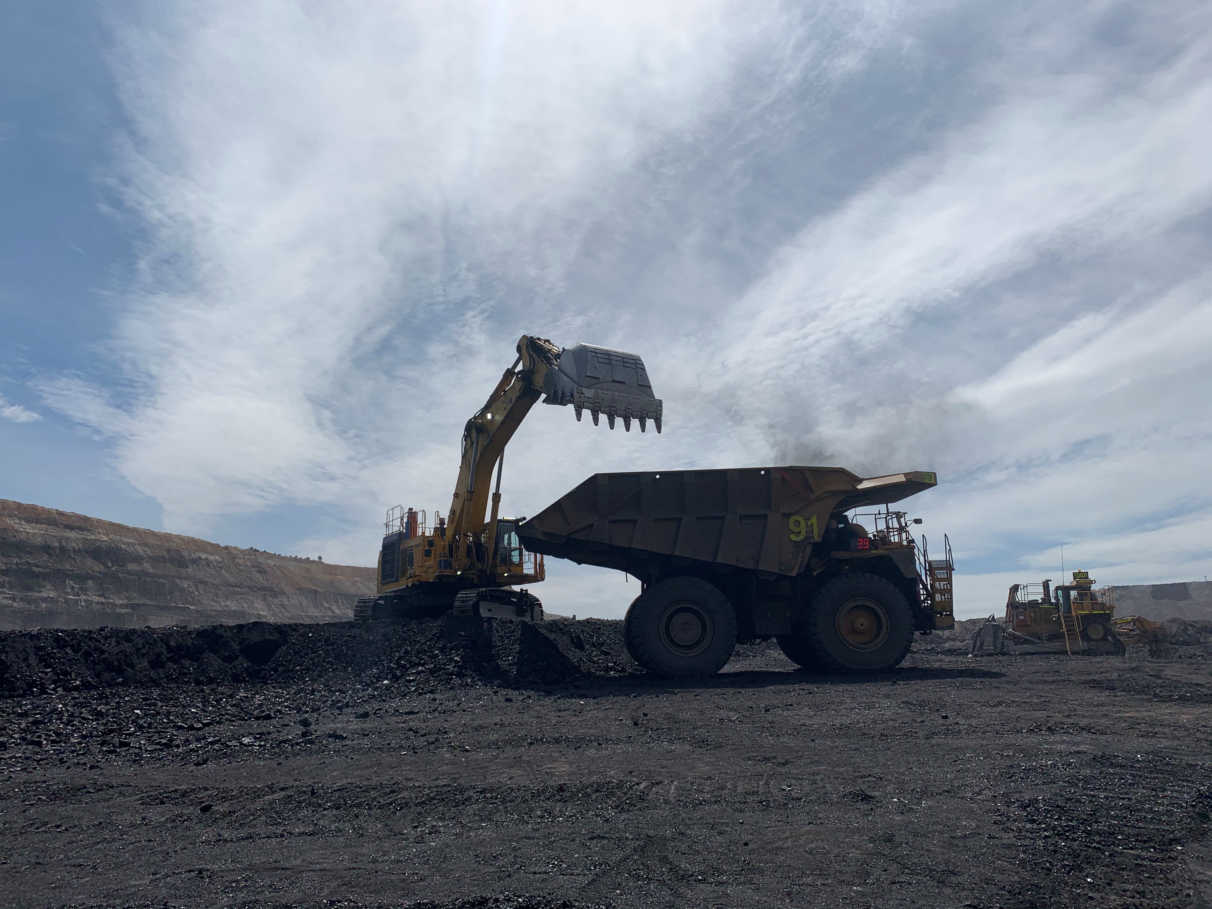 silhouetted coal mining digger next to a dump truck at a coal mine