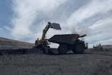 silhouetted coal mining digger next to a dump truck at a coal mine