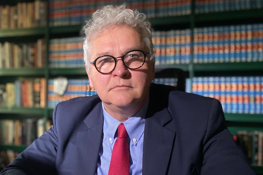 Bill Potts in his office. behind him is a wall of legal books. 