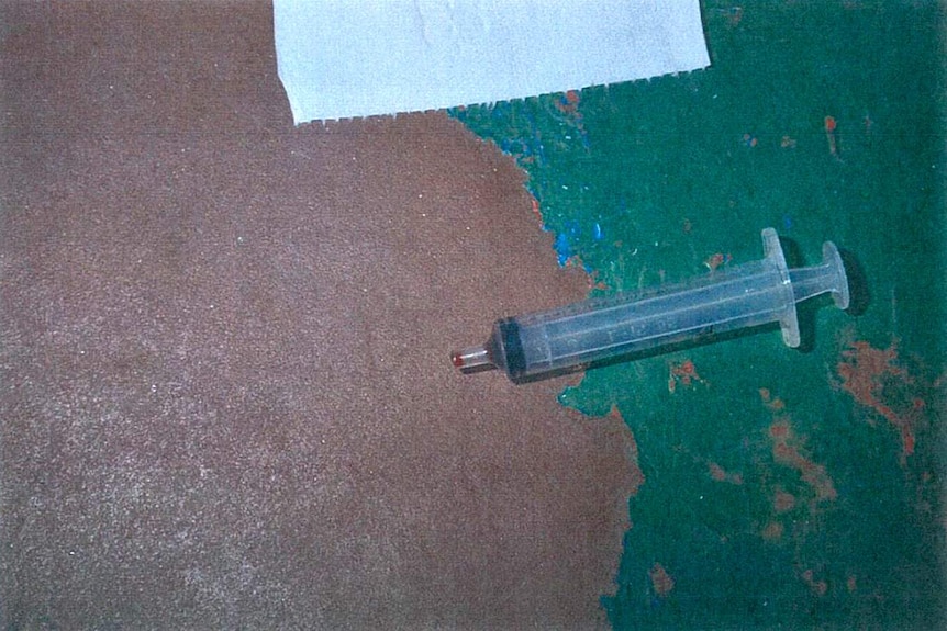 A blood-tipped syringe on the floor.