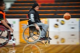 A wheelchair basketballer wheeling fast to catch the ball on a fast break