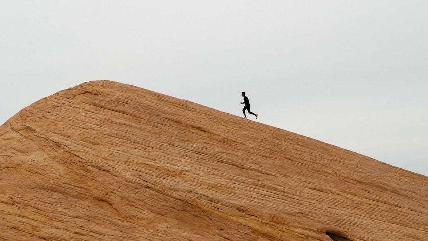 The silhouette of a runner climbing a hill.