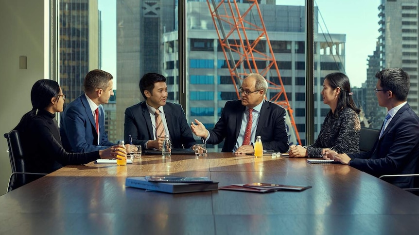 Six people sit around a CBD boardroom table