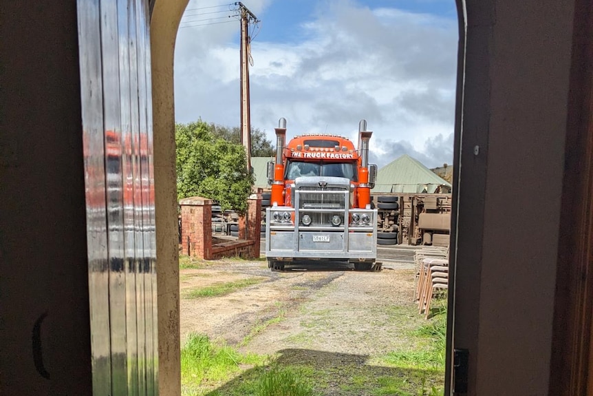 A truck driving into a driveway as seen through a doorway.
