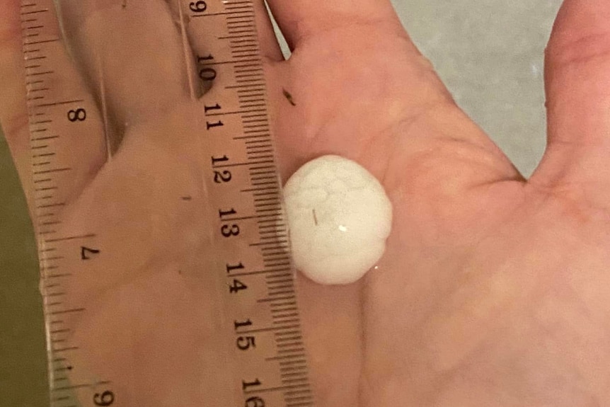 A hand holding a large hailstone.