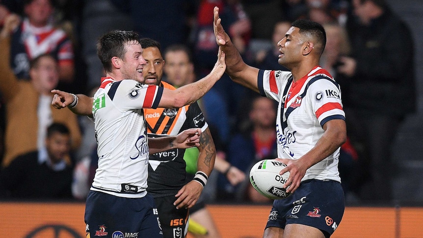 Two male rugby league players give a high five to each other as they celebrate a try.