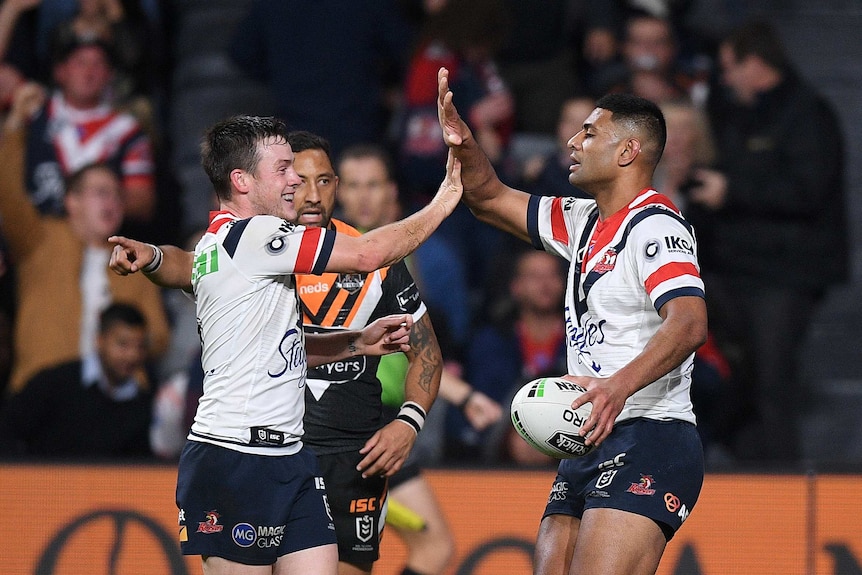 Two male rugby league players give a high five to each other as they celebrate a try.