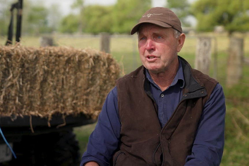 Photo of a man in front of hay bales.