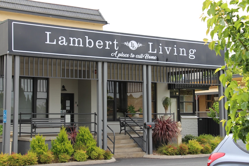 The front of a building with a veranda and stairs, a sign saying 'Lambert Living' above