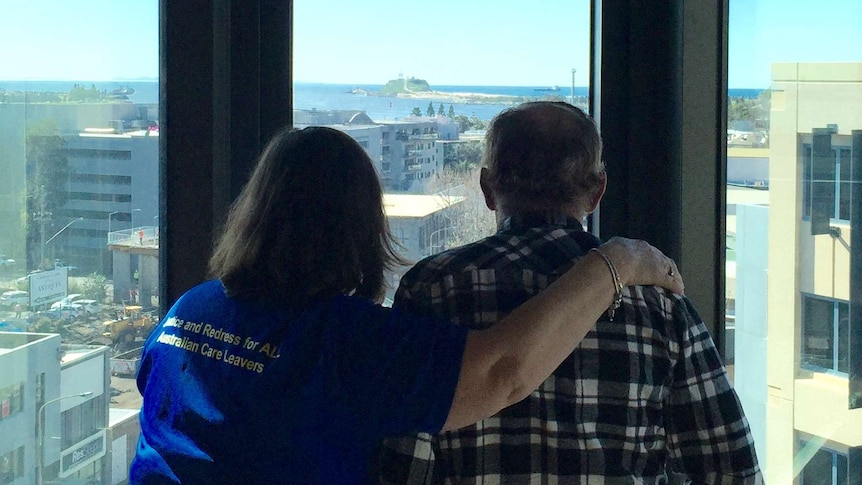 The back view of a man and a woman looking out over the city of Newcastle.