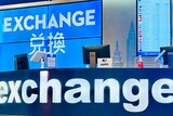 A big blue sign says 'exchange' with a TV behind it also in in blue with the word 'exchange' and Chinese lettering.