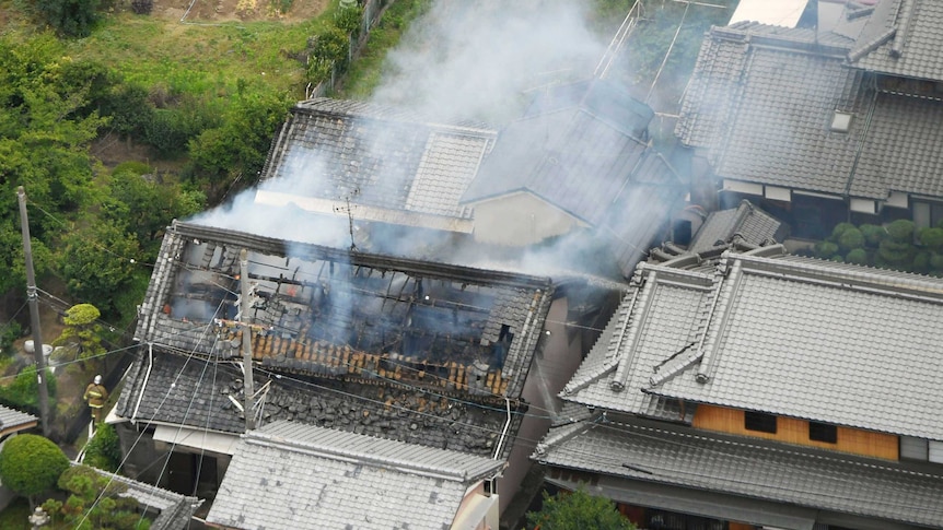 An aerial photograph shows smoke rising from a damaged house