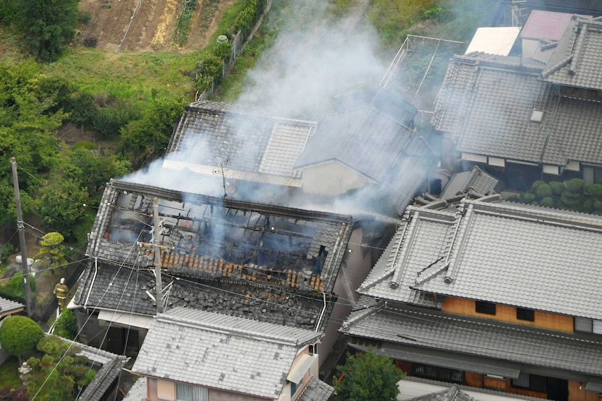 An aerial photograph shows smoke rising from a damaged house