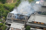 An aerial photograph shows smoke rising from a damaged house
