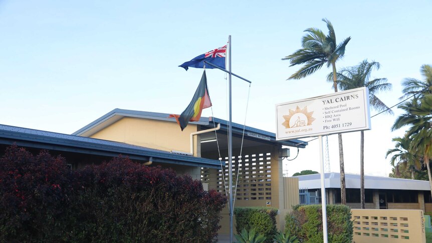 Exterior of a building with the Aboriginal and Australian flags on a flagpole out front and a sign that reads YAL Cairns.