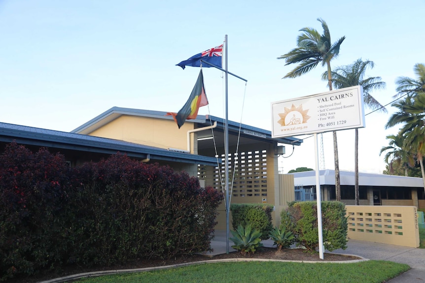 Exterior of a building with the Aboriginal and Australian flags on a flagpole out front and a sign that reads YAL Cairns.