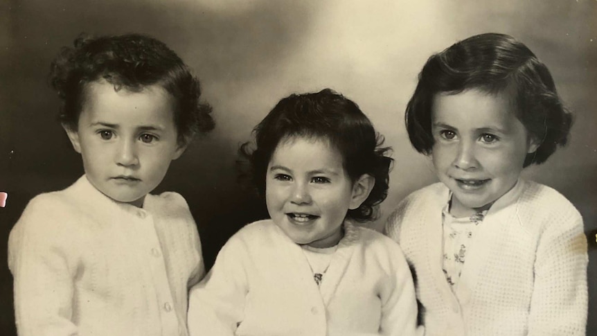 Old black and white image of three young girls sitting together