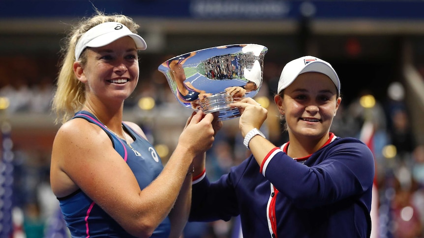 Two women hold a silver trophy between them