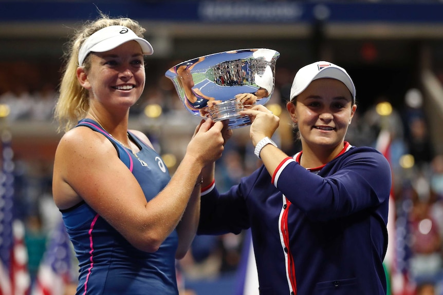 Two women hold a silver trophy between them