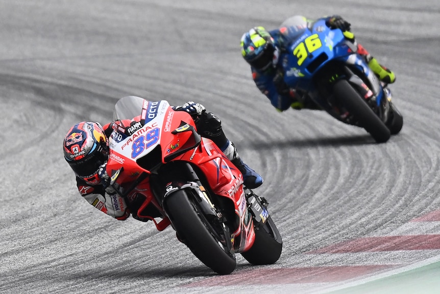 Two MotoGP bikes lead through a corner.