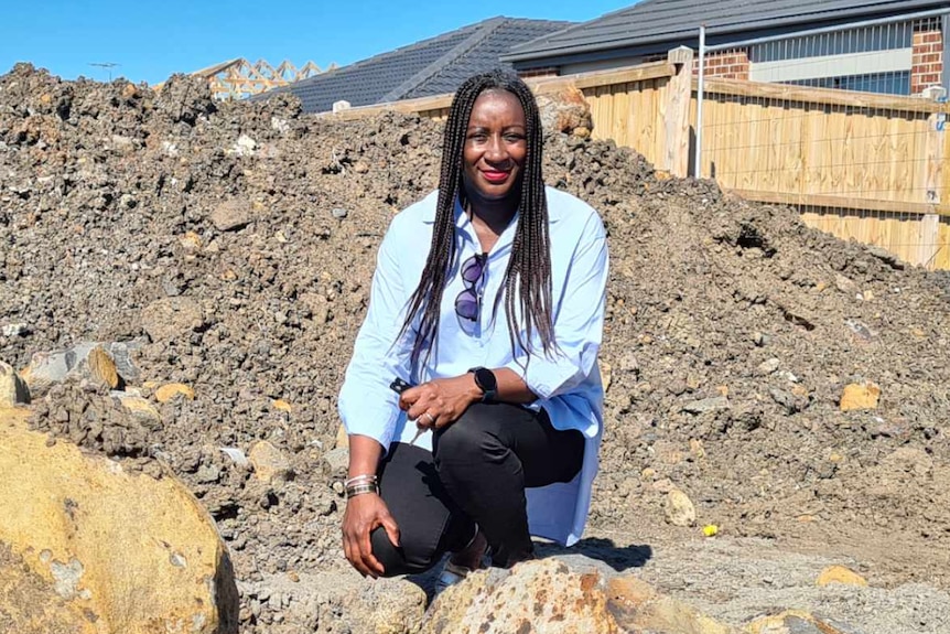 Nathalie Kapuya stands in the middle of an empty block with dirt all around her
