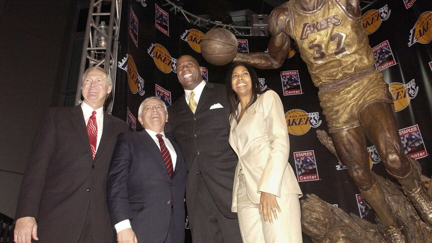 Jerry West, David Stern, Magic Johnson and his wife Cookie pose next to a statute of Johnson in Los Angeles
